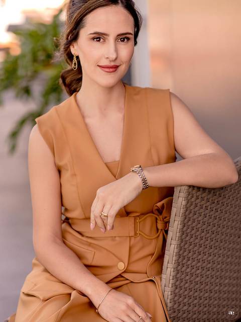 Retrato profissional da dentista Fernanda Wisniewski sentada em ambiente externo, com traje caramelo e postura descontraída, valorizando a naturalidade e a sofisticação de sua imagem profissional.'