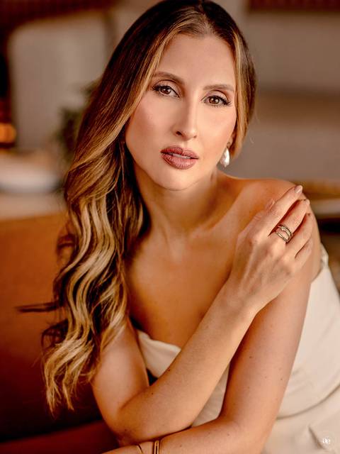 Retrato de Paloma com cabelos ondulados e mão delicadamente apoiada no ombro, valorizando os detalhes da beleza, dos acessórios e da fotografia profissional.'