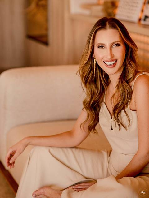 Retrato profissional da estilista Paloma sorrindo em ambiente de tons neutros, com expressão espontânea e composição que revela leveza, elegância e proximidade.'