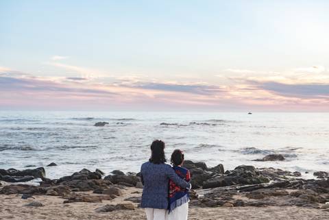 Ariane e Chistophe abraçados de costas, comtemplano o mar na praia'
