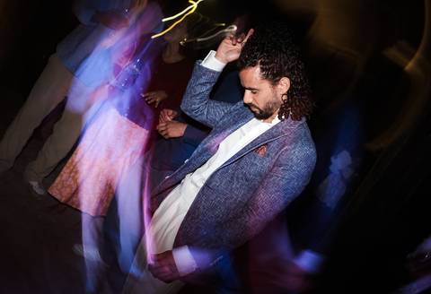 Dança dos noivos se divertindo no celeiro iluminado com luzes festivas.'