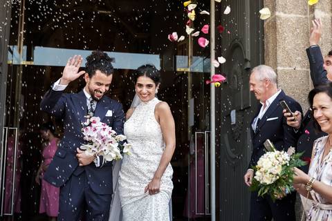 Ariane e chistophe saem sorridentes enquanto os convidados lançam arroz em celebraçao'