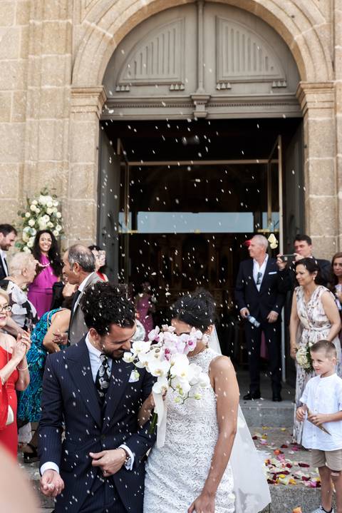 sorridentes enquanto os convidados lançam arroz em celebraçao'