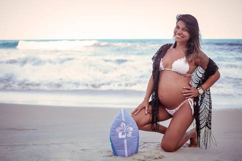 gestante de joelhos fazendo pose em acessório do bebe em seu ensaio fotográfico-RJ'