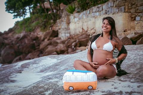 Gestante sentada nas pedras em seu ensaio fotográfico na praia da prainha/RJ'
