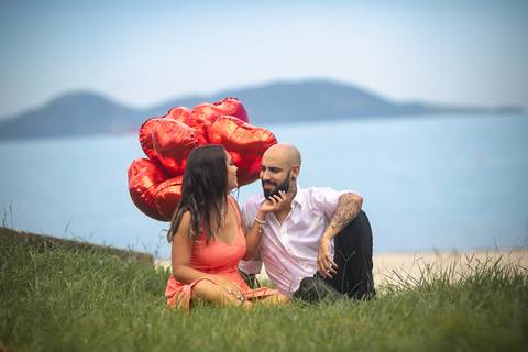 Casal sentado na grama ao fundo mar em ensaio Pré Casamento em Mangaratiba-RJ'