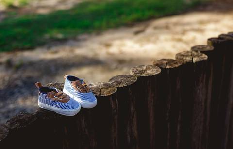 sapatinho apoiado em muro de troncos em ensaio de gestante em Grumari/RJ'