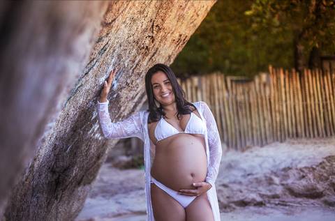 Gestante apoiada na pedra em ensaio fotográfico em Grumari/RJ'