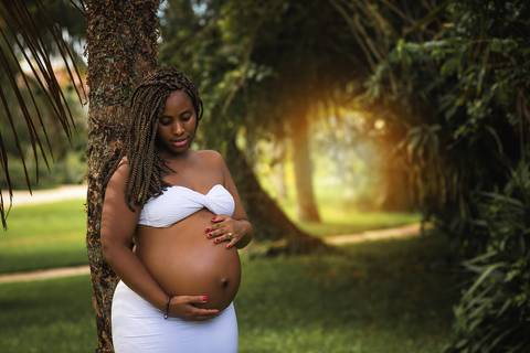 Gestante encostada em uma árvore em ensaio externo em Camboinhas/RJ'