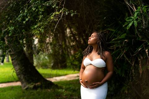 Gestante segurando a barriga com olhos fechados em ensaio externo em Camboinhas /RJ'