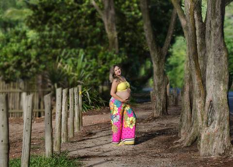 Gestante caminha perto das árvores em seu book fotográfico-RJ/Grumari'