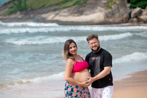 Ensaio de gestante junto com esposo ele colocando a mão na barriga em ensaio gestacional na Praia de Grumari/RJ'