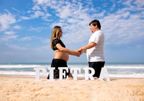gestante junto com esposo de mães dadas em ensaio de foto-prainha/RJ'