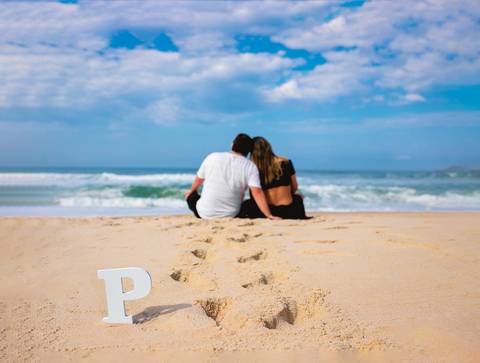 a espera de Pietra casal sentado na areia em seu ensaio gestante-prainha/RJ'