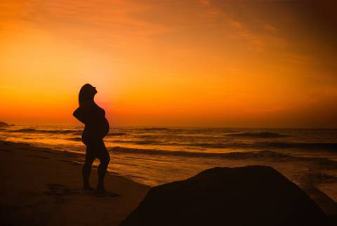 Gestante em seu ensaio ao amanhecer céu alaranjado em praia-RJ-Prainha'