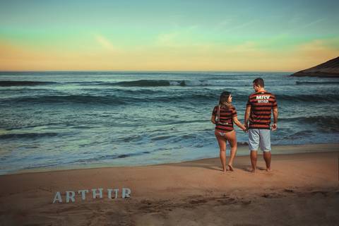 nome Arthur na areia ao fundo gestante e seu esposo em ensaio fotográfico na praia/Rj'