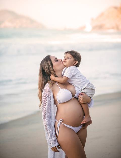 gestante dando um beijinho em seu primogênito em seu ensaio fotográfico na praia/RJ'
