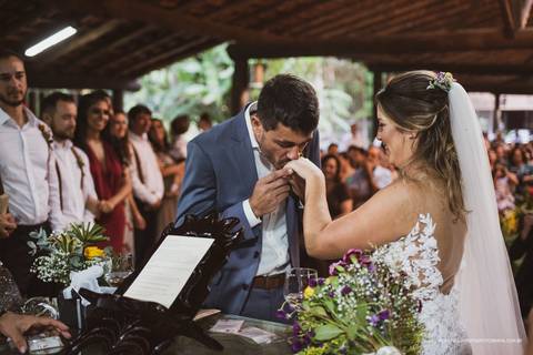 Noivo colocando a aliança na noiva '