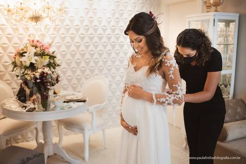 noiva gravida colocando o vestido para seu casamento de dia ao ar livre'