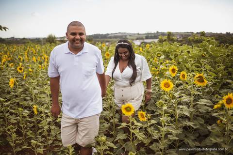 foto romantica de casal caminhando em jardim de girassol'