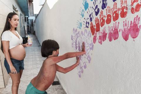 Ensaio gestante lifestyle feito com tinta e pinturas a mao filhos pai e mamae gestante em casa fotografa premiada nayara andrade fotografia de santos com fotos emocionantes do amor do lar'