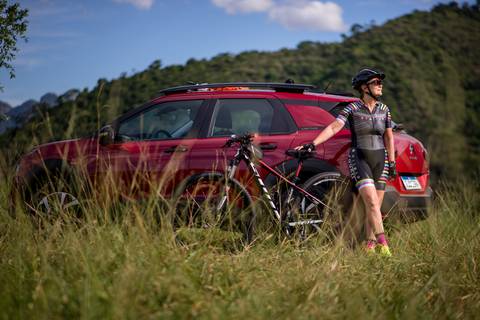 ensaio fotográfico realizado na capelinha de Ibiraçu-ES. Ciclista encostada no carro apreciando a paisagem com sua bike.'