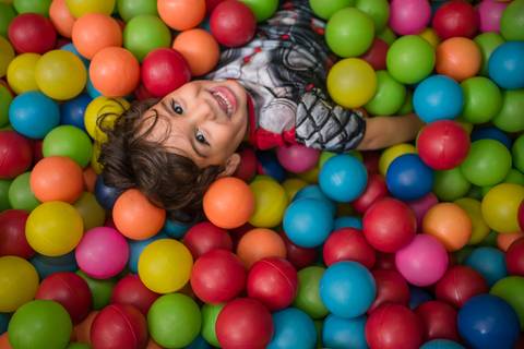 Fotografia de criança sorrindo na piscina de bolinhas no cerimonial Arca dos Sonhos em Laranjeiras, Rio de Janeiro'