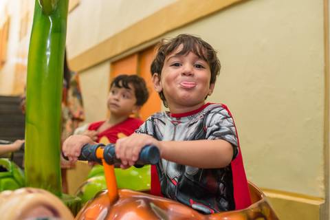 fotografia de festa infantil, criança brincando no carrossel e mostrando a língua. Cerimonial Arca dos Sonhos em Laranjeiras, Rio de Janeiro '