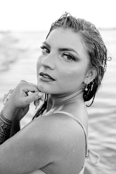Retrato feminino de ensaio fotográfico realizado em Vila Velha na praia de Itapuã. Mulher molhada olhando para câmera.'
