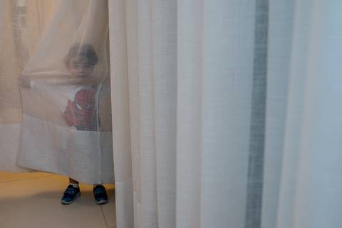 fotografia de aniversario infantil. criança escondida atrás da cortina'
