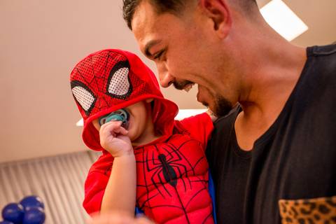fotografia homem-aranha de chupeta no colo do papai em seu aniversário infantil de 2 anos'