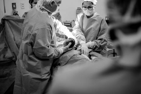 Fotografia Documental de Parto. Momento em que equipe médica está realizando o nascimento da neném. Fotografia Hospital Metropolitano, Serra, ES.'