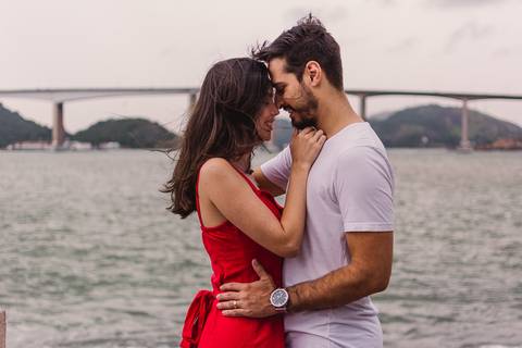 Ensaio fotográfico realizado na Ilha do Boi em Vitória. Casal próximo ao mar com vista da terceira ponte de vitória.'