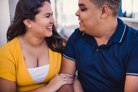 Fotografia da noiva sorrindo para o noivo. Ensaio Pré casamento realizado no Farol de Santa Lúcia em Vila Velha, ES.'