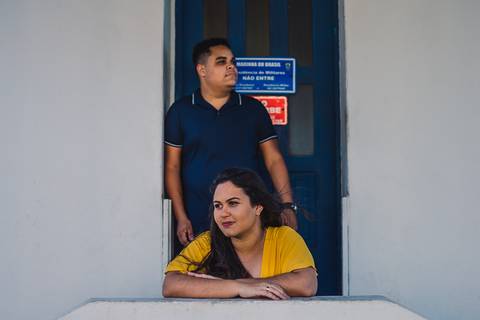 Retrato da Noiva debruçada sobre corrimão da escada e noivo encostado no beiral da porta.'