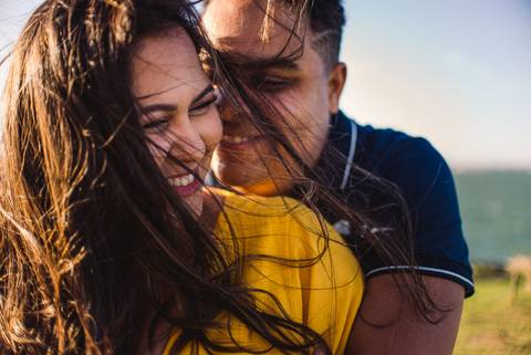 Fotografia da noiva e noivo sorridentes, abraçados. Foto no Farol de Santa Lúcia em Vila Velha, ES.'