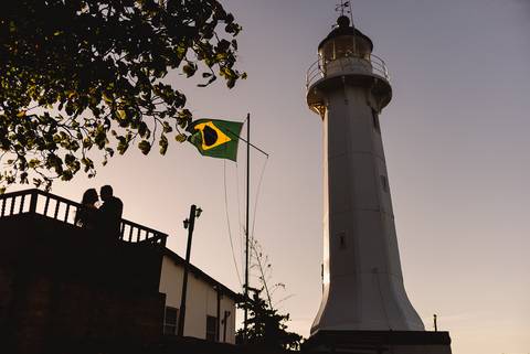 Fotografia da torre do farol de santa lúcia em vila velha. Casal está a esquerda. Foto silhueta do casal.'