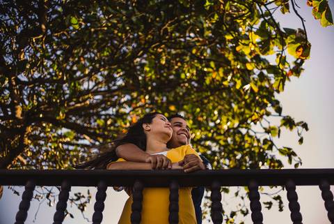 Casal debruçado e sorrindo. Olhando o horizonte. Fotografia feita no Farol de Santa Lúcia em Vila Velha, ES.'