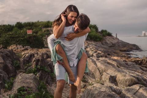 casal brincando na pedra da sereia na praia da costa, vila velha es'