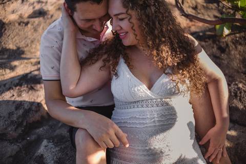 Casal sentado na pedra na pousada do farol em vila velha, no morro do moreno.'