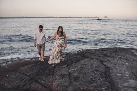 Casal andando sobre as pedras da Pousada do Farol. Vista do Mar de Vitória, Espírito Santo.'