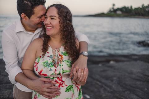 Casal sorrindo e abraçado na pedra da Pousada do Farol em Vila Velha. Morro do Moreno. Por do Sol.'