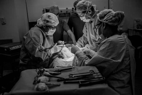Equipe médica realizando cirurgia de parto.'