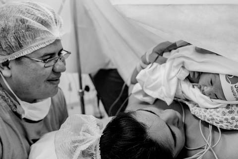 Pai, mãe e bebê. Mãe olhando para o bebê. Bebê recém nascido olhando para mãe.'