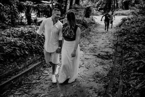Casal andando sorrindo no parque Lage no Jardim Botânico no Rio de Janeiro. Crianças correndo atrás no corredor. Fotografia Preta e Branca.'