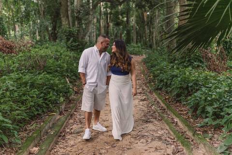 Ensaio Pré Casamento realizado no Parque Lage, no Rio de Janeiro. Casal andando e olhando um para o outro na rua de terra no parque.'