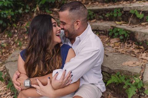 Casal sorrindo, sentados na escadaria do Parque Lage. '