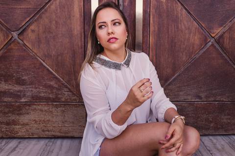 Ensaio fotográfico na Ilha do Frade, Vitória - ES. Ensaio Pessoal. Modelo sentada em frente a porta de madeira.'