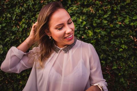 Ensaio fotográfico pessoal. Modelo sorrindo, passando a mão no cabelo. '