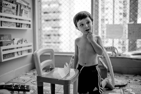 Aniversariante contando história dos 3 porquinhos para família. Fotografia Documental de Família. Aniversário Infantil em Itapuã, Vila Velha, ES.'